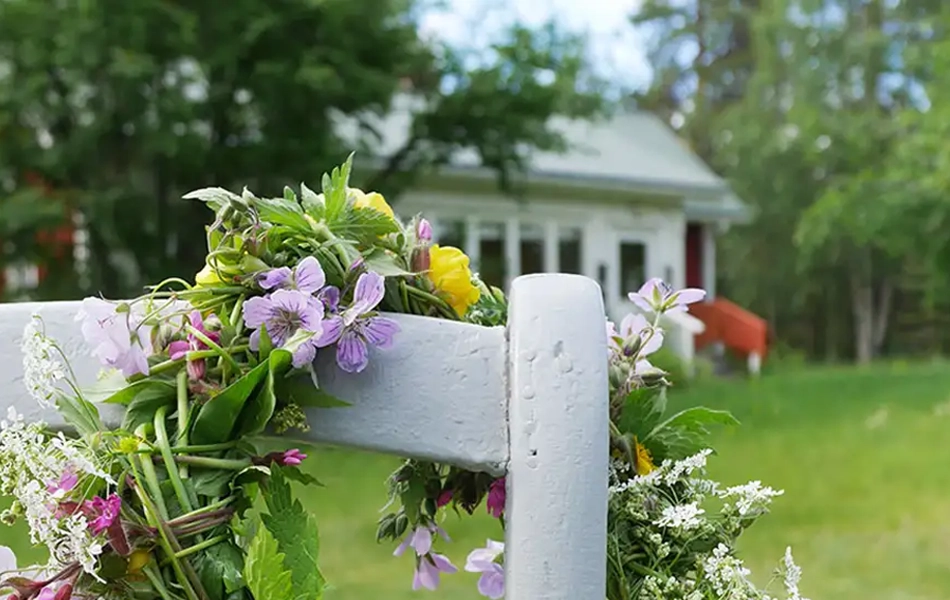 Sommerlicher Blumenkranz hängt an einer weißen Stuhllehne